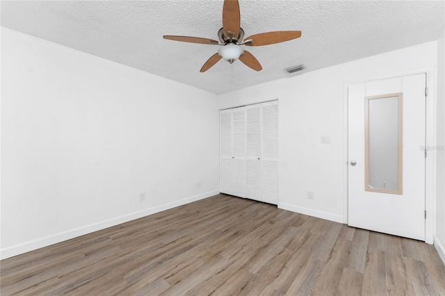 unfurnished bedroom with ceiling fan, light hardwood / wood-style floors, a closet, and a textured ceiling