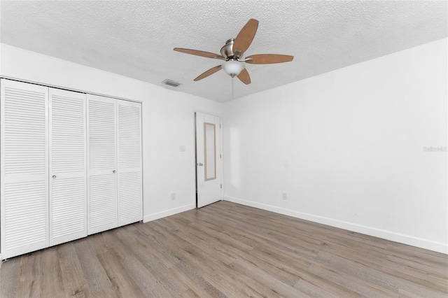 unfurnished bedroom featuring ceiling fan, a closet, light hardwood / wood-style floors, and a textured ceiling