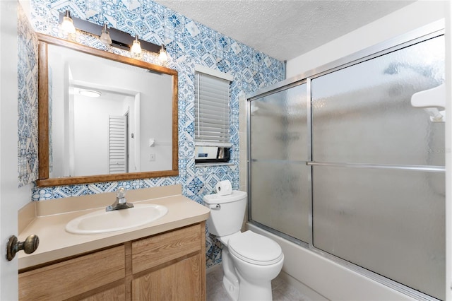 full bathroom with vanity, combined bath / shower with glass door, toilet, and a textured ceiling