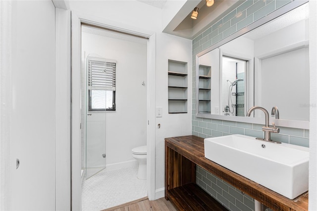 bathroom featuring sink, decorative backsplash, toilet, and walk in shower