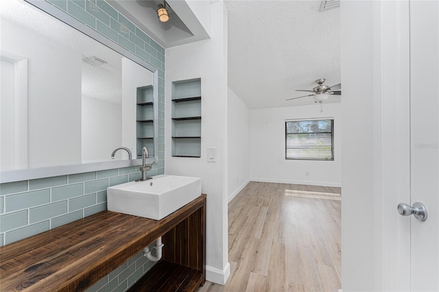 bathroom featuring tasteful backsplash, sink, hardwood / wood-style flooring, ceiling fan, and a textured ceiling