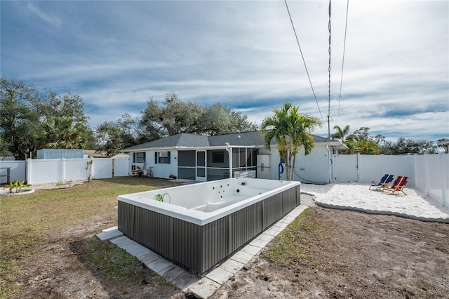 back of property featuring a hot tub, a sunroom, and a yard