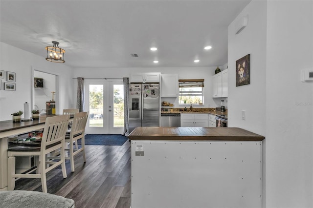 kitchen with french doors, stainless steel appliances, kitchen peninsula, decorative light fixtures, and white cabinets