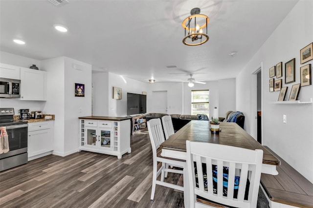 dining room with dark hardwood / wood-style floors and ceiling fan with notable chandelier