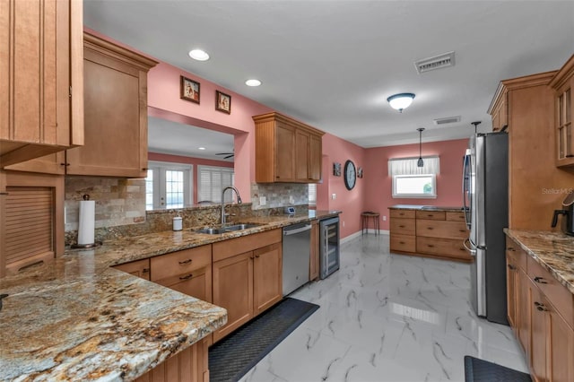 kitchen with hanging light fixtures, sink, appliances with stainless steel finishes, tasteful backsplash, and beverage cooler