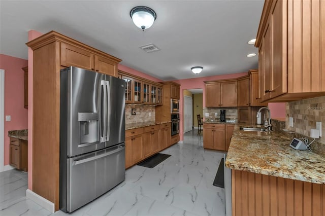 kitchen with light stone counters, sink, appliances with stainless steel finishes, and tasteful backsplash