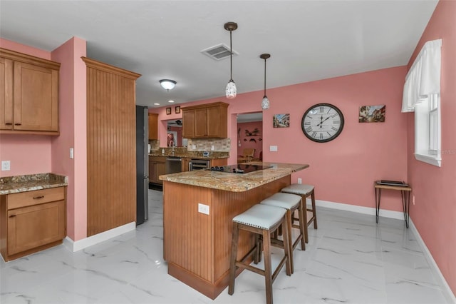 kitchen with light stone counters, stainless steel dishwasher, pendant lighting, a kitchen bar, and a kitchen island