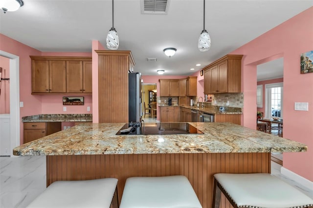 kitchen featuring kitchen peninsula, appliances with stainless steel finishes, tasteful backsplash, a breakfast bar, and pendant lighting