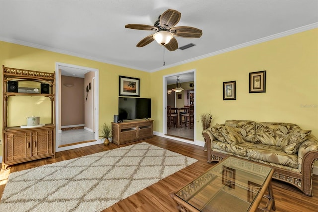 living room featuring hardwood / wood-style floors, ceiling fan, and crown molding