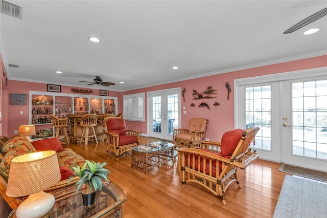 living room featuring french doors, light wood-type flooring, ceiling fan, and ornamental molding