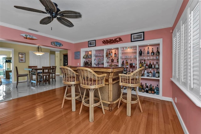 bar with decorative light fixtures, hardwood / wood-style flooring, ceiling fan, and crown molding