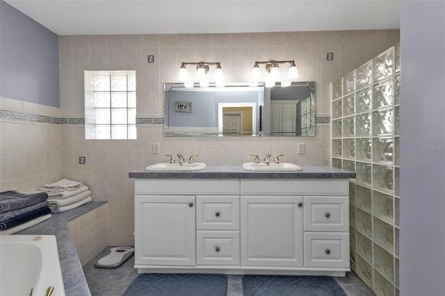 bathroom featuring a tub to relax in, tile patterned flooring, vanity, and tile walls