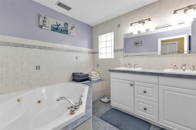 bathroom with tile patterned floors, a bathtub, tile walls, and vanity