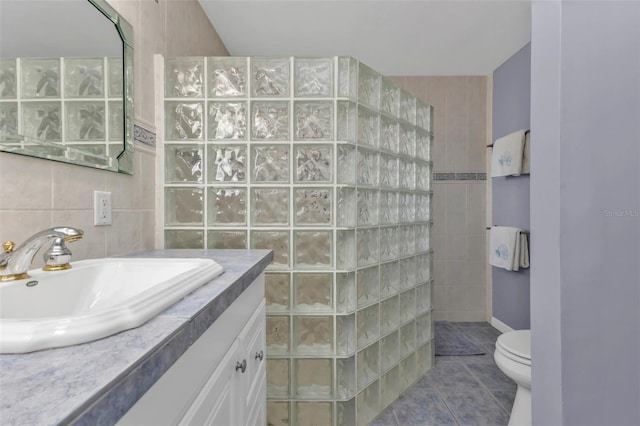 bathroom with tile patterned floors, vanity, a shower, tile walls, and toilet