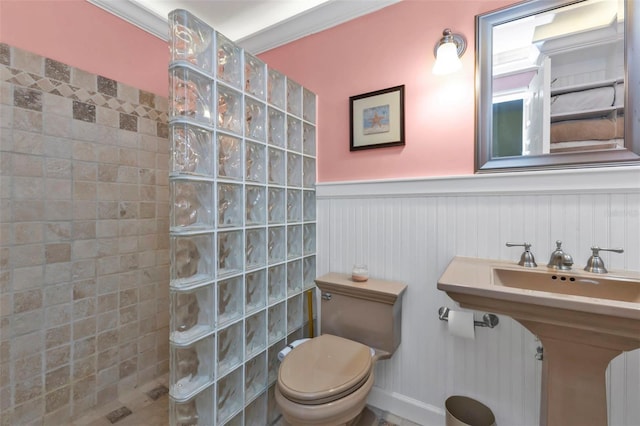 bathroom with a tile shower, ornamental molding, and toilet