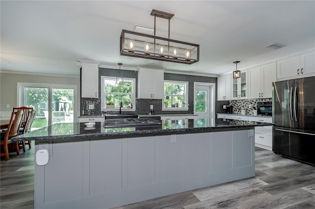 kitchen with stainless steel fridge, decorative light fixtures, dark stone countertops, white cabinets, and a kitchen island