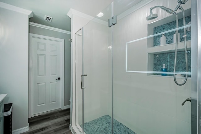 bathroom with hardwood / wood-style floors, crown molding, and walk in shower