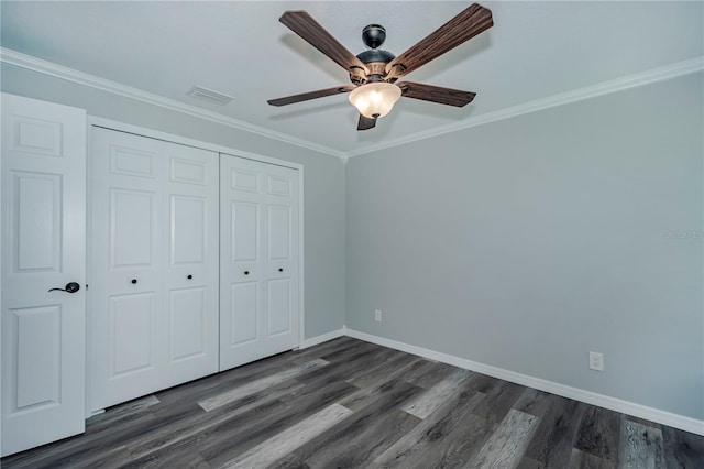 unfurnished bedroom with ceiling fan, dark hardwood / wood-style floors, crown molding, and a closet