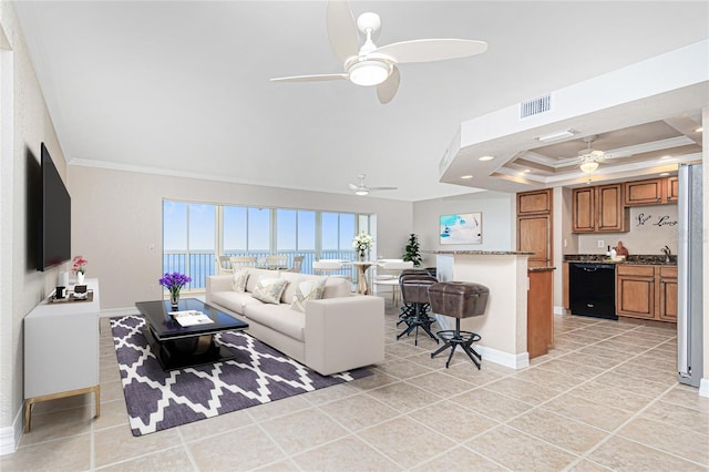 living room featuring ceiling fan, light tile patterned flooring, crown molding, and a raised ceiling