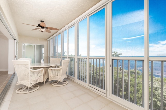 unfurnished sunroom with ceiling fan, a water view, and a healthy amount of sunlight