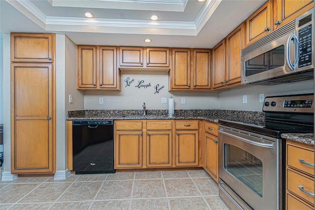 kitchen with a raised ceiling, dark stone countertops, crown molding, and stainless steel appliances