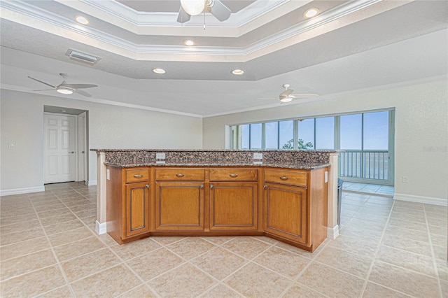 kitchen with light tile patterned floors, a tray ceiling, ornamental molding, and a center island