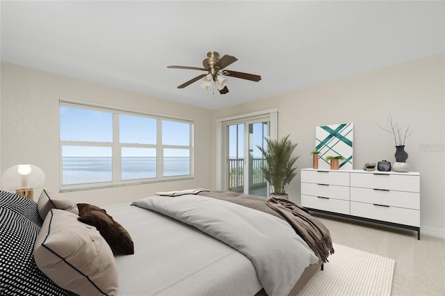 carpeted bedroom featuring a water view, ceiling fan, access to exterior, and multiple windows