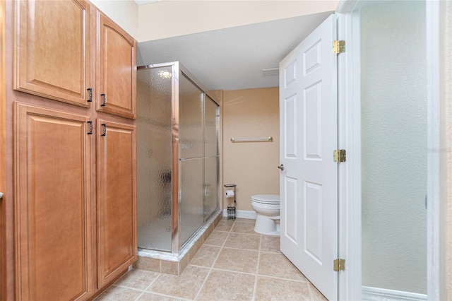 bathroom featuring toilet, tile patterned floors, and a shower with door