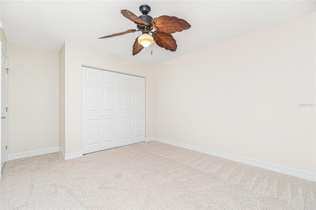 unfurnished bedroom with ceiling fan, a closet, and light carpet