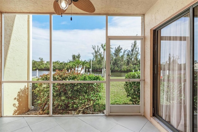 unfurnished sunroom featuring ceiling fan and a water view