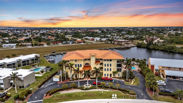 aerial view at dusk featuring a water view