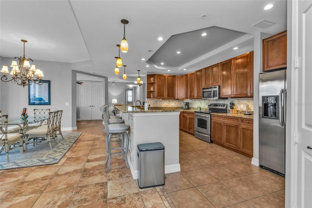 kitchen featuring appliances with stainless steel finishes, decorative light fixtures, a breakfast bar area, and a notable chandelier