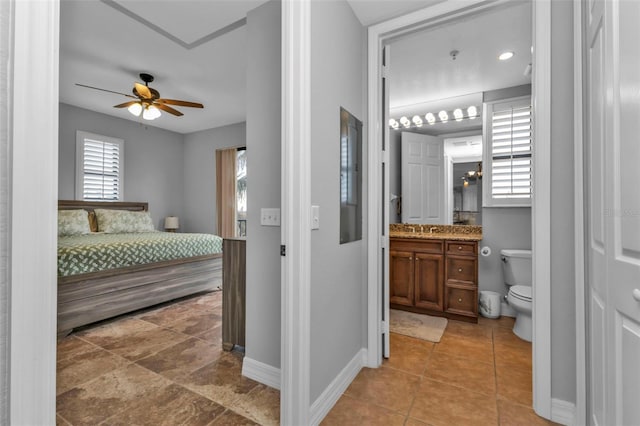 bedroom featuring connected bathroom, ceiling fan, and sink