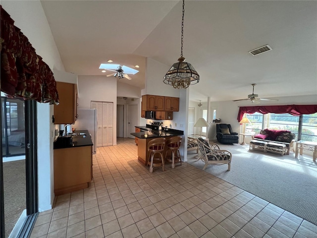 kitchen featuring ceiling fan, light colored carpet, vaulted ceiling, decorative light fixtures, and a breakfast bar area