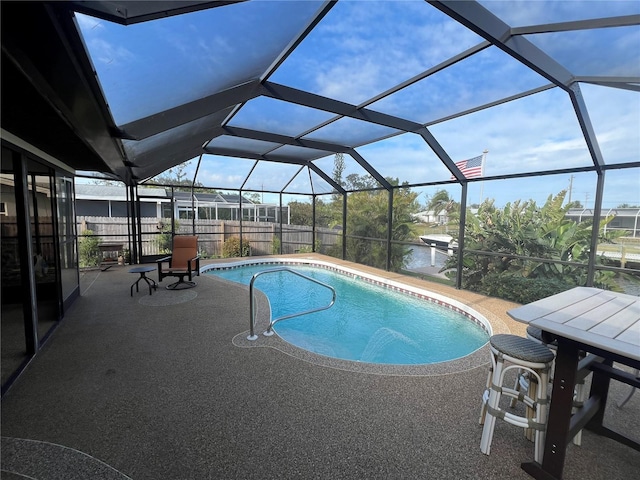 view of swimming pool featuring glass enclosure, a water view, and a patio