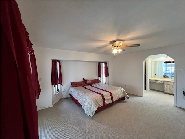 bedroom featuring light carpet, ceiling fan, and connected bathroom