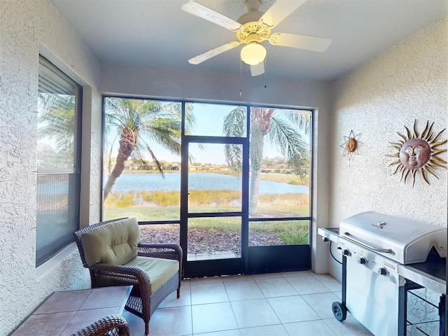 sunroom / solarium with ceiling fan and a water view