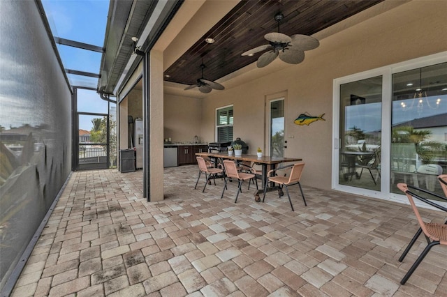 view of patio featuring a lanai, ceiling fan, and exterior kitchen