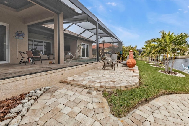 view of patio featuring a water view, ceiling fan, and a lanai