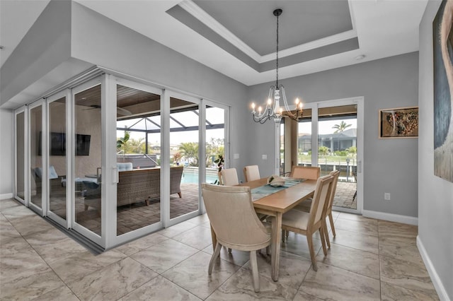 dining space featuring a notable chandelier, a tray ceiling, and ornamental molding