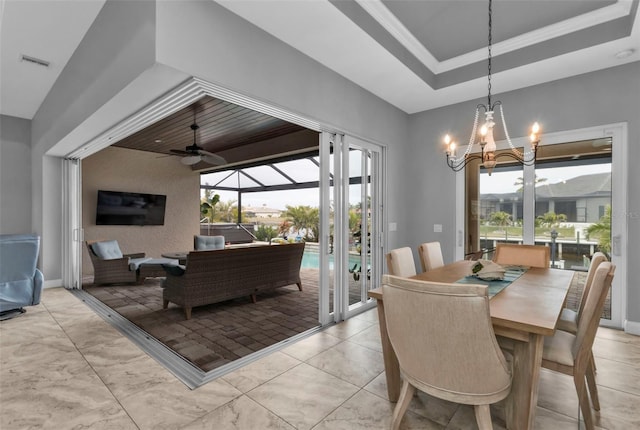 dining area featuring a tray ceiling and ceiling fan with notable chandelier