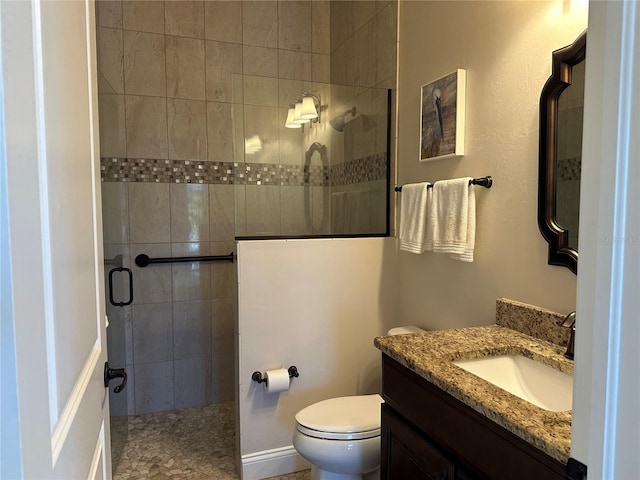 bathroom featuring vanity, a shower with shower door, and toilet