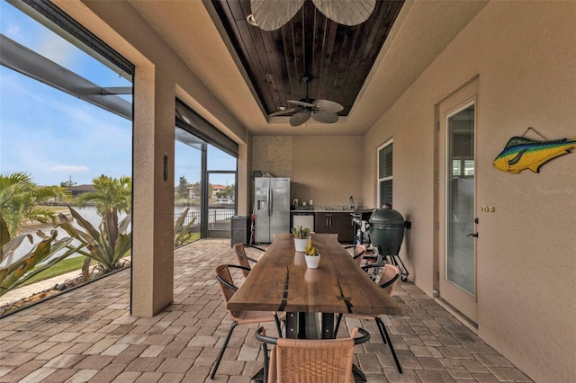 sunroom / solarium with ceiling fan and a water view