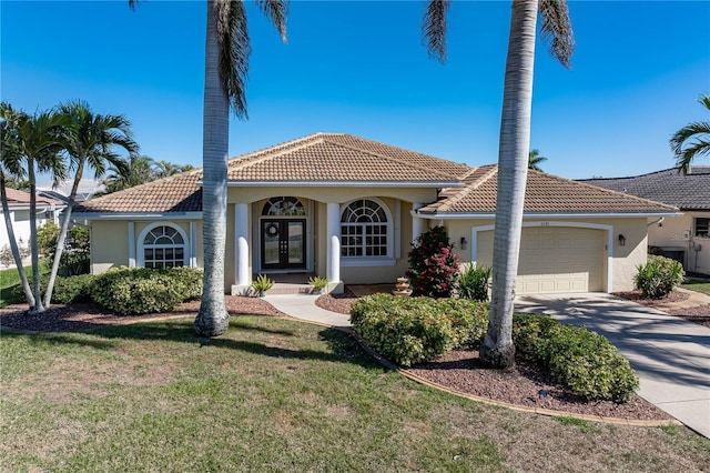 mediterranean / spanish home featuring a garage, french doors, and a front lawn