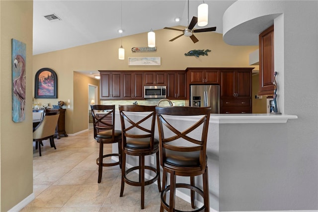 kitchen with ceiling fan, a kitchen breakfast bar, high vaulted ceiling, decorative backsplash, and appliances with stainless steel finishes