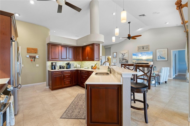 kitchen with stainless steel refrigerator, sink, hanging light fixtures, kitchen peninsula, and decorative backsplash