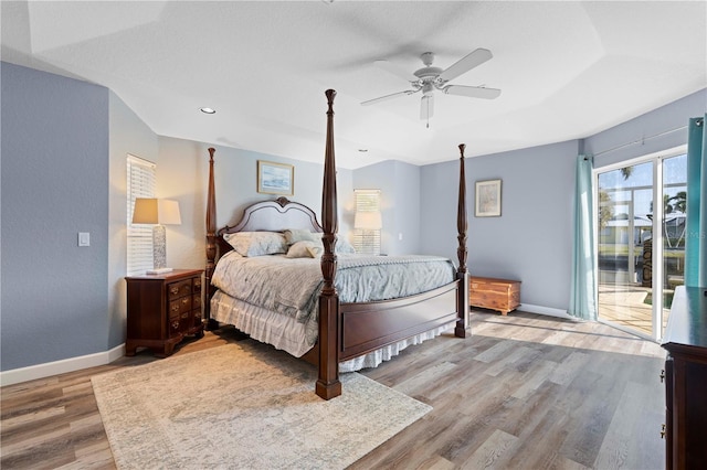 bedroom with a raised ceiling, ceiling fan, light hardwood / wood-style floors, and access to exterior