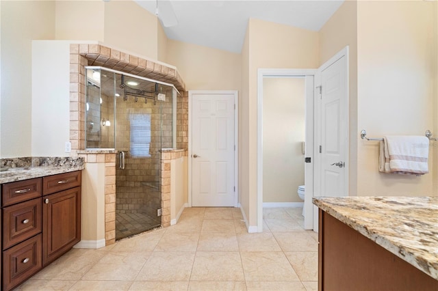 bathroom with tile patterned floors, vanity, toilet, and an enclosed shower