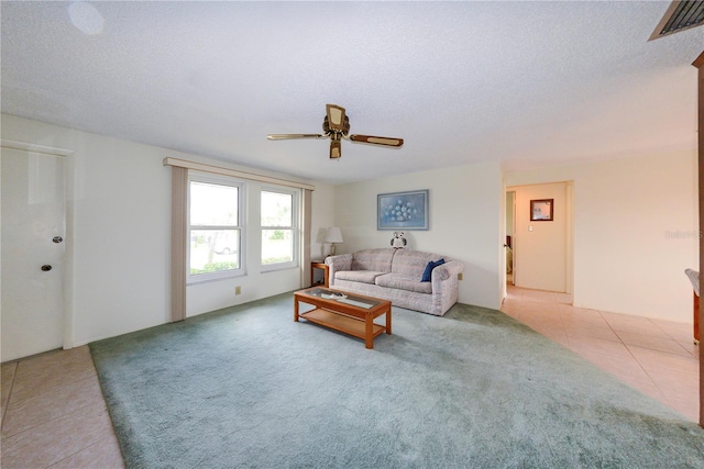 tiled living room with ceiling fan and a textured ceiling