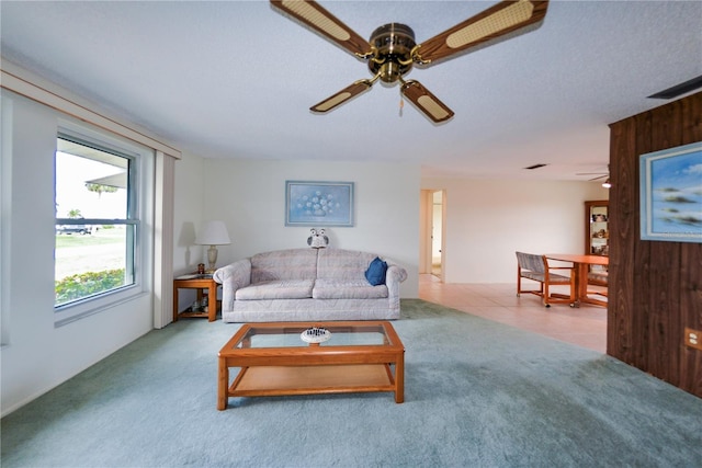 carpeted living room with a textured ceiling and wood walls